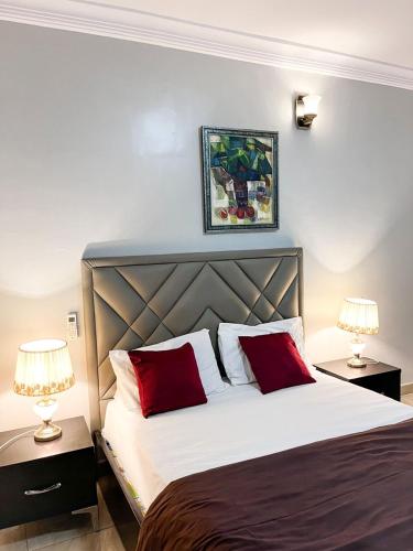 a bedroom with a bed with red pillows and two lamps at Bronx Suite by Jaynice Homes in Lekki
