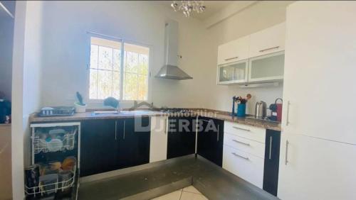 a kitchen with white cabinets and a counter top at Mille & une nuit in Al Maqārisah