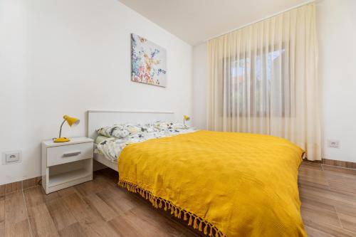 um quarto com uma cama com um cobertor amarelo em Apartment LaPePa em Šilo