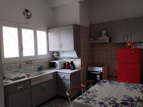 uma cozinha com armários brancos e um frigorífico vermelho em Ήσυχο σπίτι στο Μικρολίμανο em Piraeus