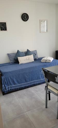 1 dormitorio con 1 cama azul y reloj en la pared en Departamento temporal por día y/o semana en Bahía Blanca