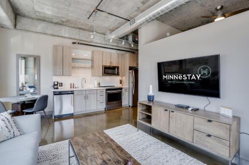 a kitchen and living room with a television on a wall at Sable 27 - One Bedroom in Minneapolis