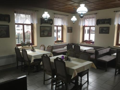 a dining room with tables and chairs and windows at Pension Formanka in Splzov