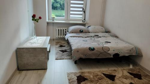 una camera da letto con un letto, un tavolo e una finestra di Apartament nad fontanną a Rzeszów