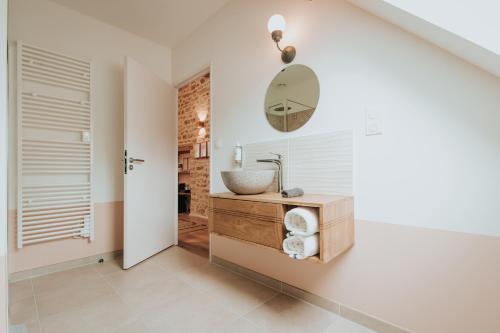 een badkamer met een wastafel en een spiegel aan de muur bij Les Cabottes in Change