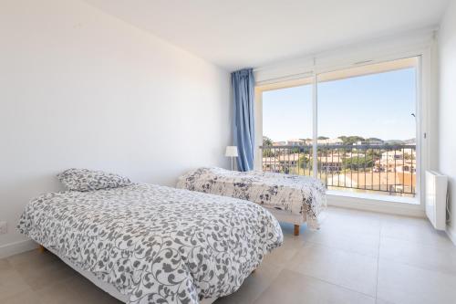 a bedroom with two beds and a large window at Giens - Vue mer / marais - Appartement refait à neuf in Hyères