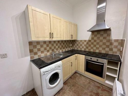 uma cozinha com uma máquina de lavar roupa e um lavatório em 2 bed flat, 1 bed flat Torquay, Torbay, Devon em Torquay