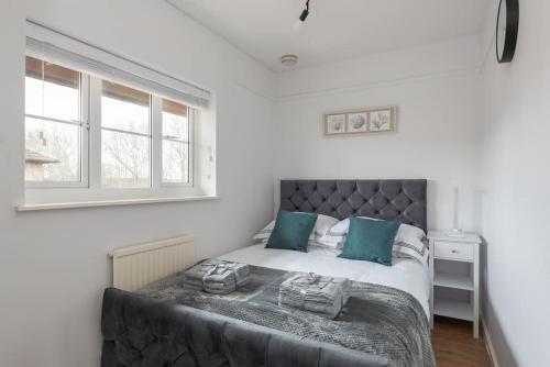 um quarto com uma cama com almofadas azuis e uma janela em Detached House - 5 mins drive to City Centre - Free Parking, Fast Wi-Fi and Smart TV with Sky TV and Netflix by Yoko Property em Milton Keynes