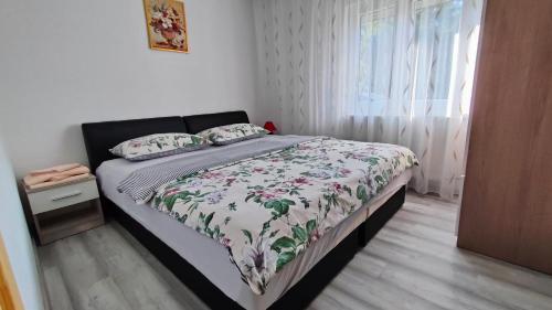 a bedroom with a bed with a floral bedspread and a window at Apartment Tina Gračac in Gračac