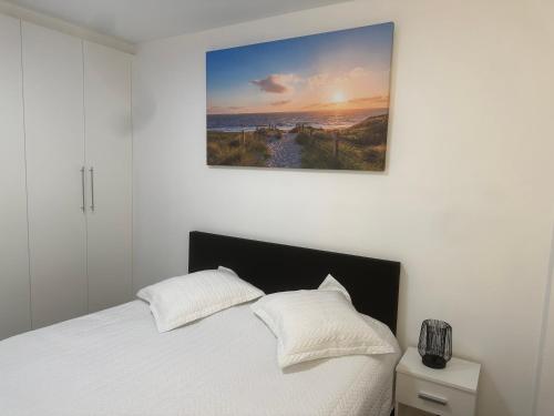 ein Schlafzimmer mit einem weißen Bett und einem Gemälde an der Wand in der Unterkunft Appartement Justine in Blankenberge