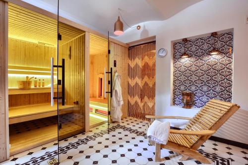 a bathroom with a glass shower and a chair at Apartamenty Willa & sauny in Kudowa-Zdrój