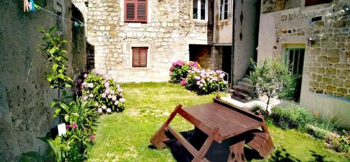 a garden with a bench and flowers in front of a building at RABSKI DVOR in Rab