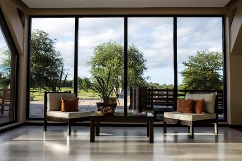 two chairs and a coffee table in front of a large window at Ayres del Champaqui Hotel Boutique Experiencial & Spa in Villa General Belgrano