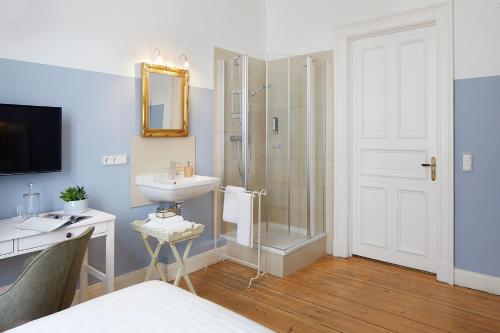 ein Bad mit einer Dusche, einem Waschbecken und einem Spiegel in der Unterkunft Hotel am Museum in Hamburg