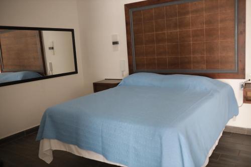 um quarto com uma cama azul e um espelho em Hotel Posada Huasteca em Tamazunchale