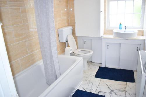 a bathroom with a tub and a toilet and a sink at The Hathway Walk Home in Bristol