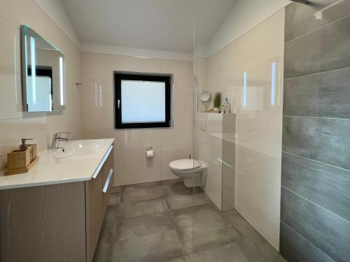 a bathroom with a sink toilet and a window at Chalet Charivari Inzell mit Whirlpool, Sauna & Garten in Inzell