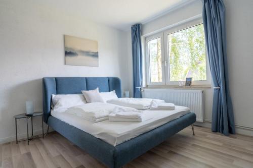 - un lit dans une chambre avec une tête de lit bleue et une fenêtre dans l'établissement 2-Zimmer-Wohnung in Meeresnähe, à Neustadt in Holstein