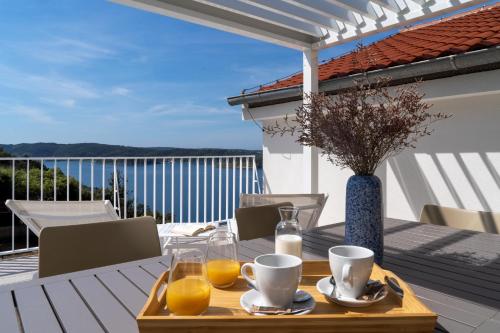 a table with a tray of orange juice on a balcony at Zlatni Zalaz,Apartments,Supetarska Draga in Supetarska Draga