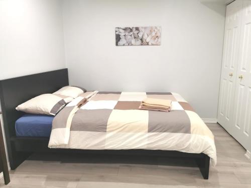 een slaapkamer met een bed met een gestreepte deken bij Perfect location comfort private house lower level 2 bedroom unit in Mississauga