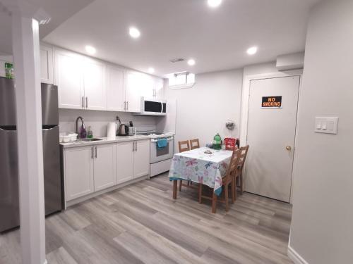 una cucina con armadi bianchi e tavolo con sedie di Perfect location comfort private house lower level 2 bedroom unit a Mississauga