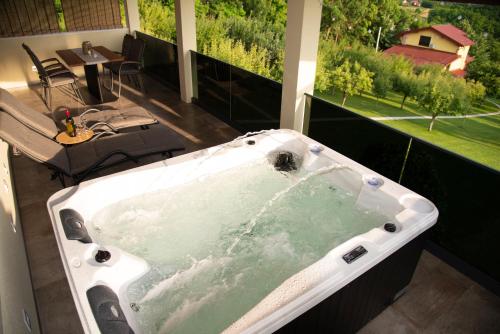 un'ampia vasca da bagno in un balcone con tavolo e sedie. di Guest House Blažević a Tucilača