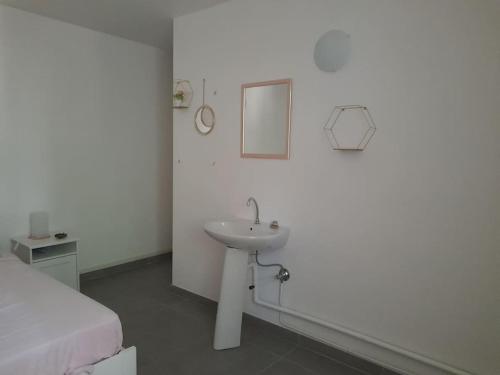 a white bathroom with a sink and a bed at Maison T3 70M2 avec jardin in Lattes