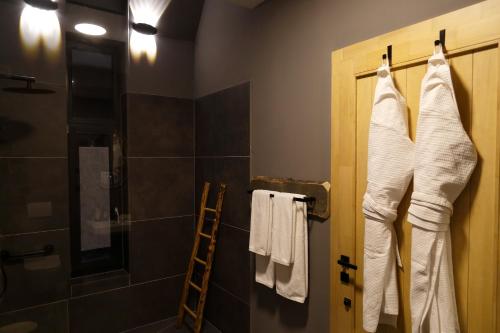 ein Bad mit einer Dusche und Handtüchern, die an einer Tür hängen in der Unterkunft PORTAL Village Only Adults in Sibiel