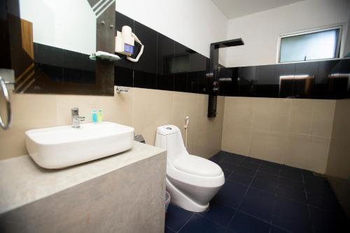 a bathroom with a white sink and a toilet at Hotel Eden Garden in Sigiriya