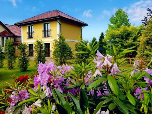 a yellow house with flowers in front of it at Home Apartments 17 in Kołobrzeg