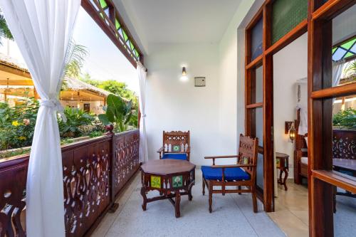 a room with a balcony with chairs and a table at TASNEEM islamic luxury suites in Jambiani