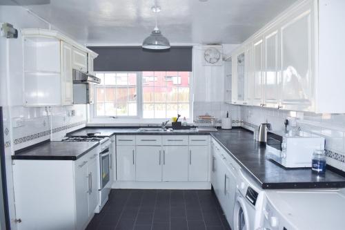 a white kitchen with white cabinets and black counter tops at The Hathway Walk Home in Bristol