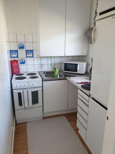 una pequeña cocina con armarios blancos y fregadero en Studio Helmi, en Taalintehdas