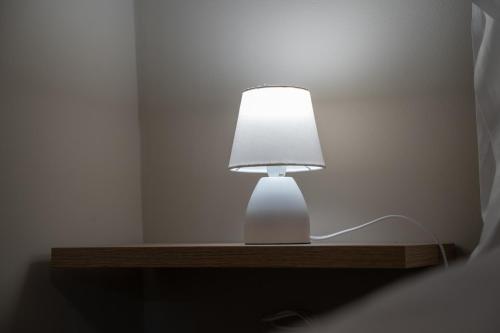 a white lamp sitting on a wooden table at Casa Sautu-fau in Santa Venerina