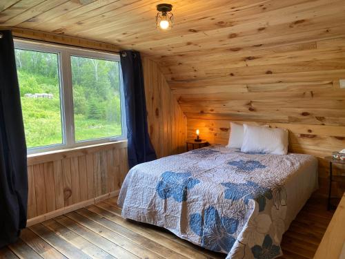 a bedroom with a bed in a log cabin at Le Hangar in La Malbaie