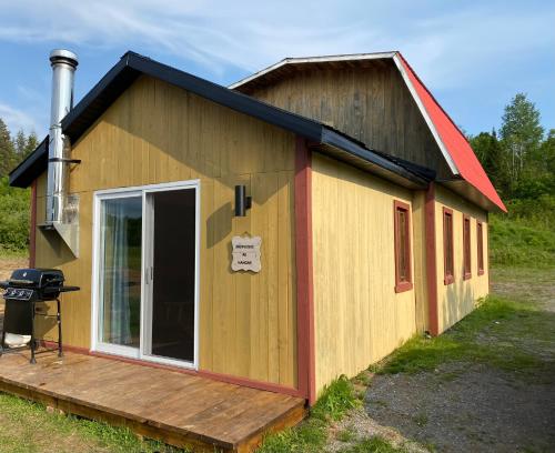 a small building with a deck and a grill at Le Hangar in La Malbaie