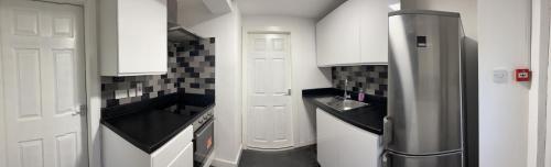 a kitchen with white cabinets and a stainless steel refrigerator at The Crescent, Flat 1 - Stockport, Manchester in Manchester