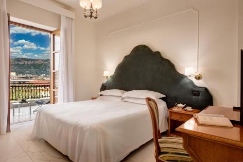 a bedroom with a large bed and a desk and a window at Majestic Palace Hotel in Sant'Agnello