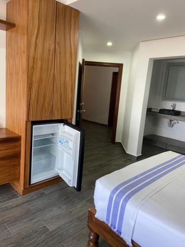 a hotel room with a bed and a refrigerator at HOTEL EL CORAL in Punta Mita