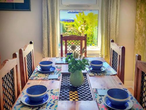 a dining room table with a vase of flowers on it at Firwood Apartment in Kilmun