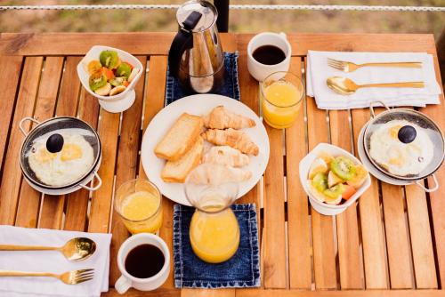 a wooden table with a plate of breakfast foods and orange juice at Glamping Sunset Hill Salamina-Caldas in Aranzazu