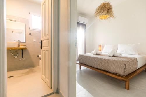 a white bedroom with a bed and a bathroom at Dohos Skiathos Suites in Skiathos