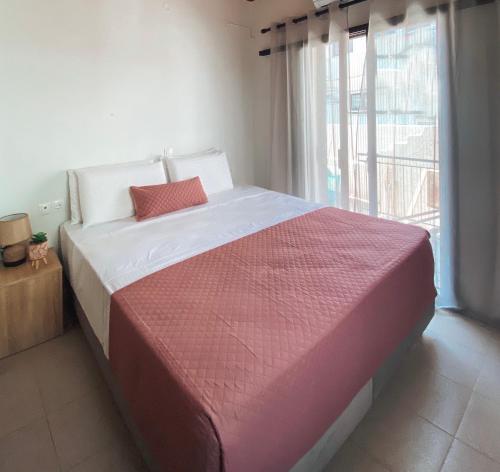 a bedroom with a large bed with a large window at Pueblo Viejo in Lefkada Town