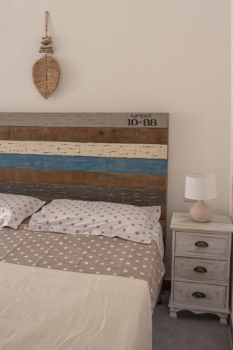 a bedroom with a bed with a wooden headboard and a night stand at Teia Holiday Apartments in Vulcano