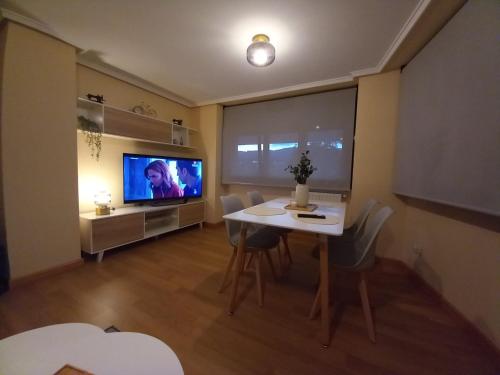 a living room with a dining table and a television at Apartamento Aurora in Villaviciosa