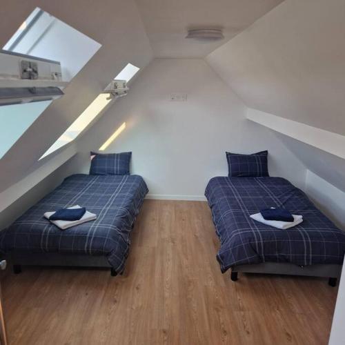 two beds in a attic bedroom with a attic at appartement à 20 minutes de Paris St Lazare et Stade de France in Sannois