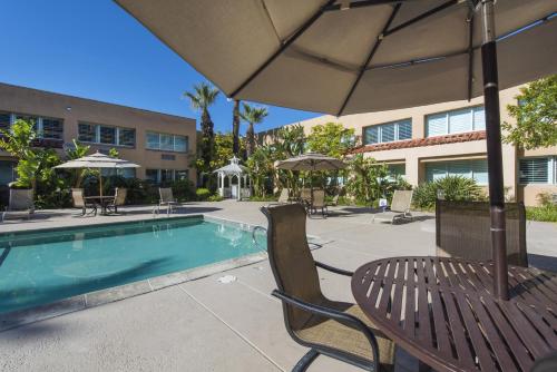 a patio with chairs and an umbrella next to a pool at Grand Vista Hotel in Simi Valley