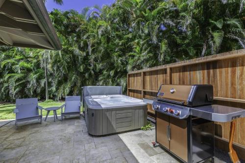 a backyard patio with a grill and chairs and trees at Hale Nanea home in Kilauea