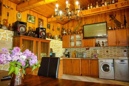 Albena Guest House في شابلا: مطبخ مع خزائن خشبية وطاولة مع الزهور الأرجوانية
