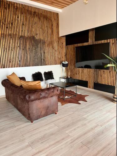 ein Wohnzimmer mit einem braunen Sofa und einem Tisch in der Unterkunft DMM SUITS in Boé